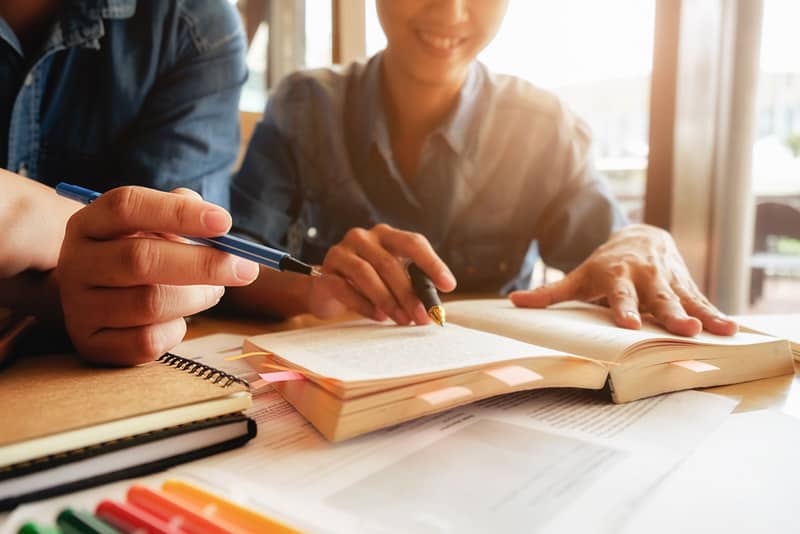 英語の教科書で勉強する二人の日本人女性、英語の学生